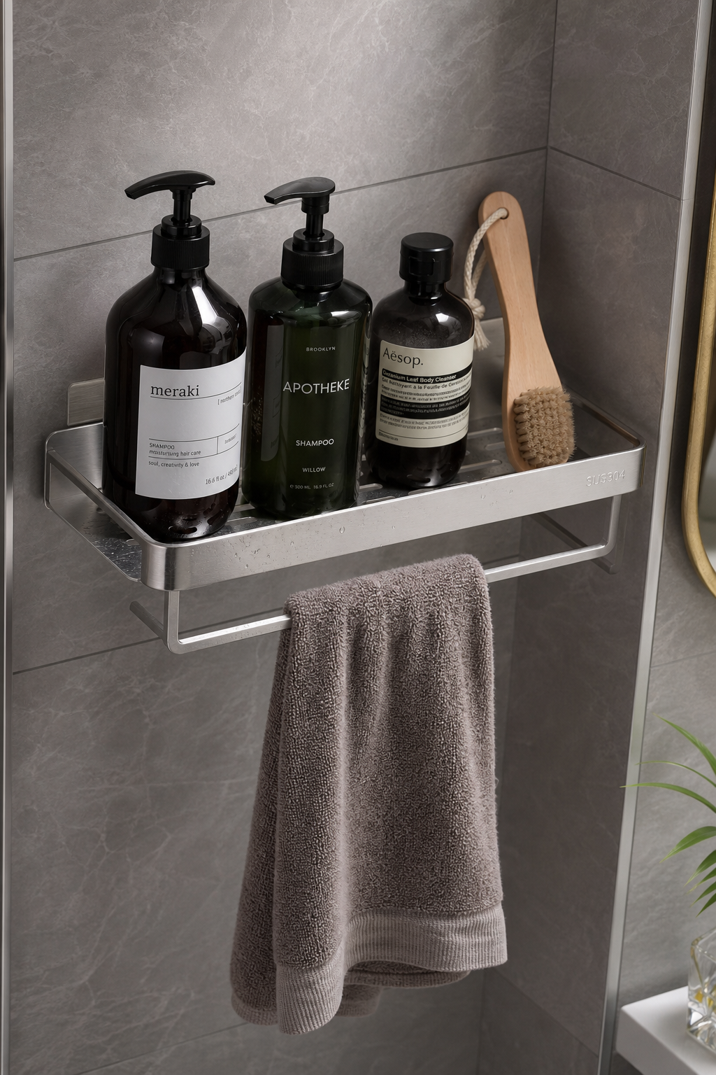 stainless steel no-drill bathroom shelf installed on a tiled corner wall, neatly arranged shampoo bottles, cleaning brush, folded towel, visible drainage gaps, realistic moisture-resistant material rendering, soft top light, high-end product photography