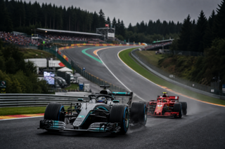 Formula 1 Belgian Grand Prix at Spa-Francorchamps, dramatic overcast race atmosphere, silver Mercedes leading red Ferrari through Eau Rouge, long-lens motorsport photography, high detail, editorial sports magazine style