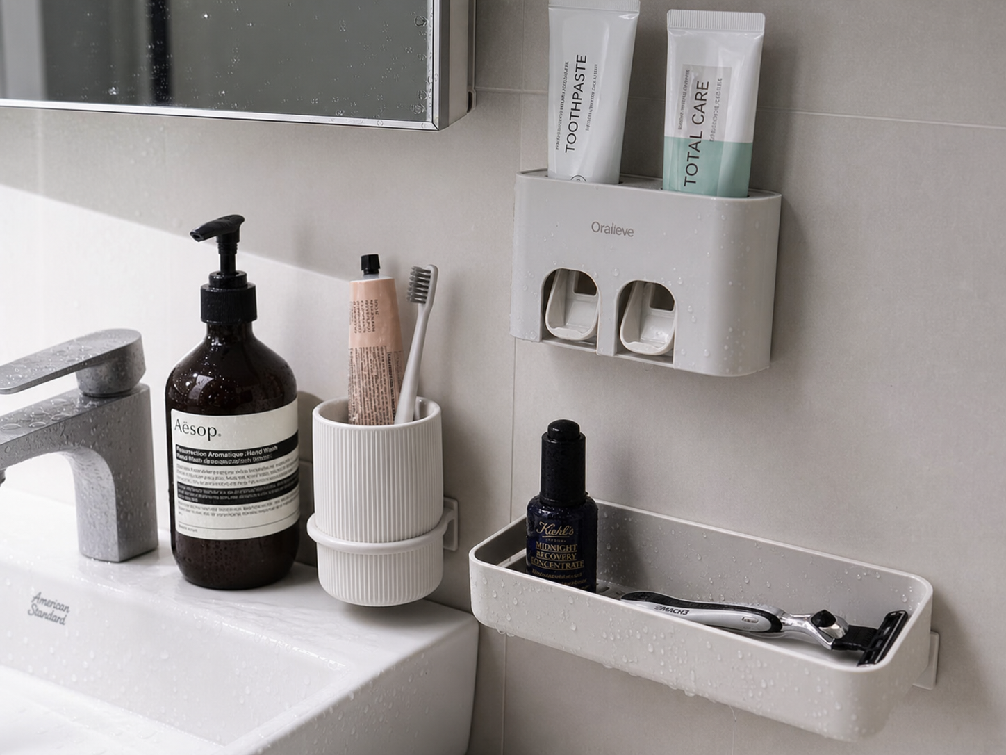 Tight sink-area close-up in a Korean studio apartment bathroom, toothpaste hanger mounted on smooth tile, toothbrush cup holder, small plastic tray for grooming items, crisp side lighting, realistic water droplets, high-detail home organization photo