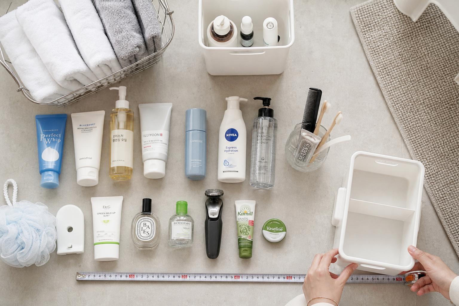 flat lay of small bathroom organizing session, grouped toiletries, measurement tape, minimal storage bins, Korean studio apartment lifestyle, bright realistic overhead shot