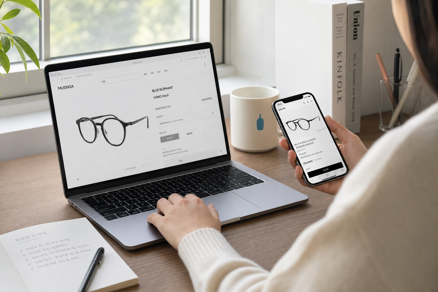 clean Korean lifestyle desk scene, person comparing eyeglasses product descriptions on laptop and smartphone, soft daylight, minimal stationery, realistic product research mood