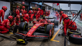 tense Formula 1 pit lane moment, Ferrari car released from pit box with mechanics and equipment, broadcast-style freeze-frame composition, realistic motorsport documentary look